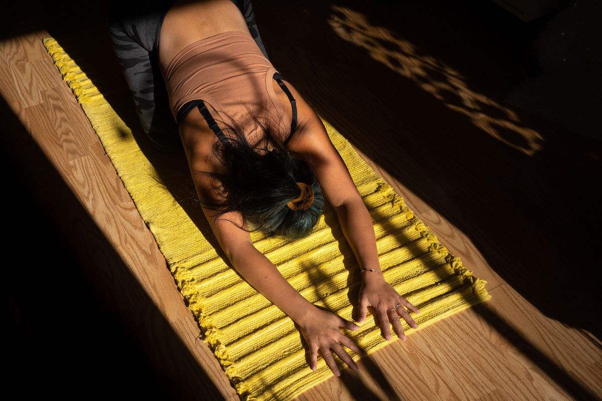 Frau sitzt auf Yogamatte und beugt sich nach vorne.